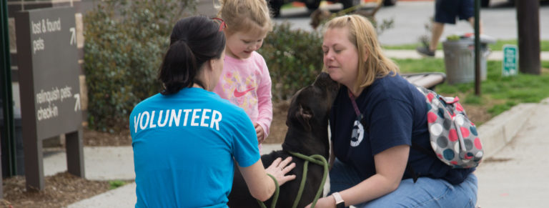 volunteer helping a pet owner with her daughter and dog