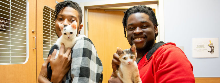 Two young men holding their adopted kittens at DeKalb County Animal shelter.