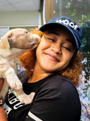 LifeLine supporter, Yeseina, soaks up puppy kisses in her Woof merch.