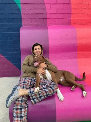 Adopted dog, Colby, cuddles up to his pawrent in front of a colorful Atlanta mural.
